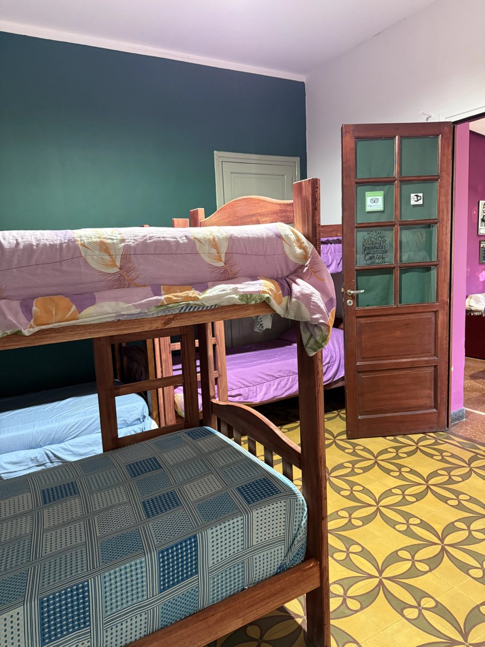 Habitación compartida con varias cuchetas de madera y puerta vidriada