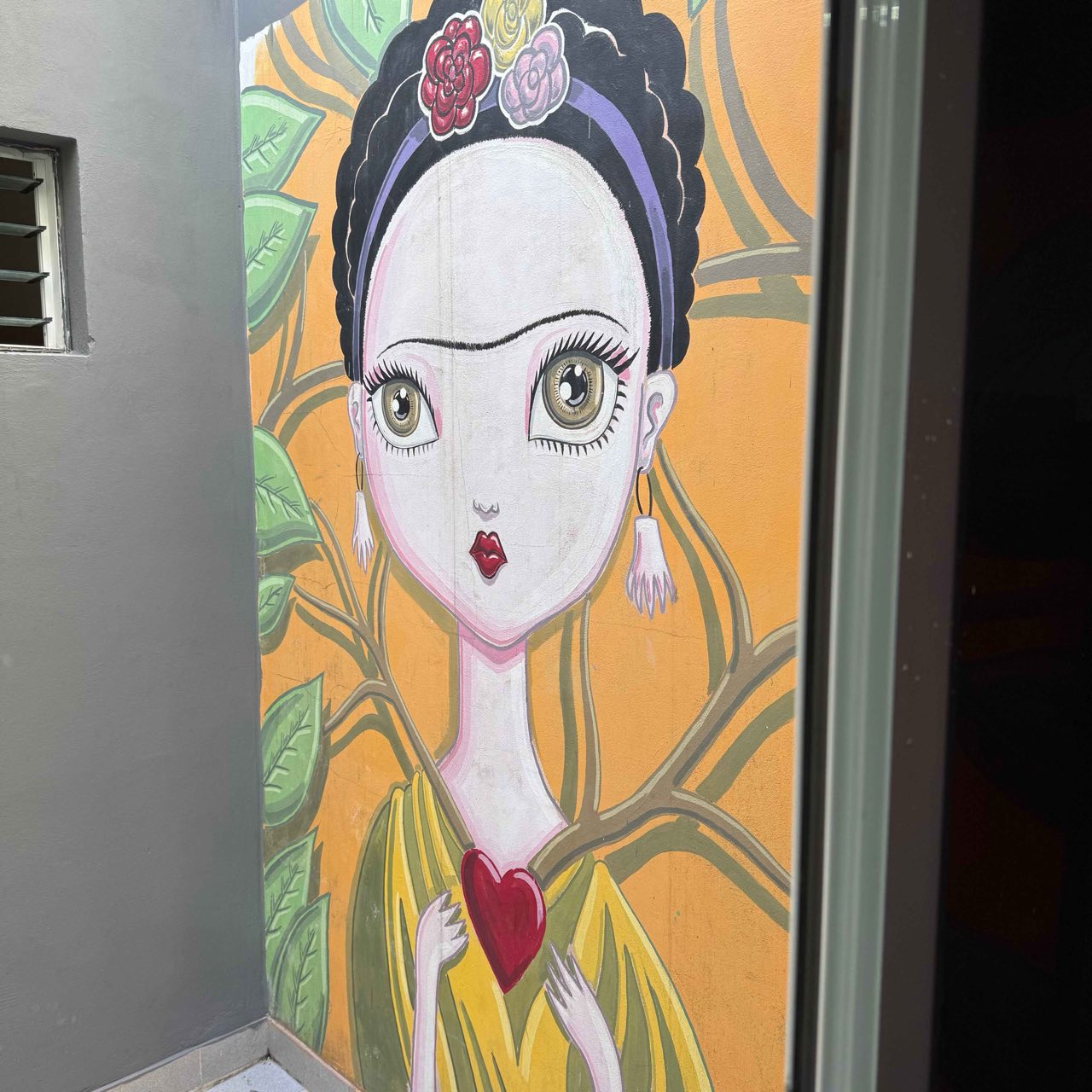 Mural artístico de una Frida estilizada en una pared de la casa