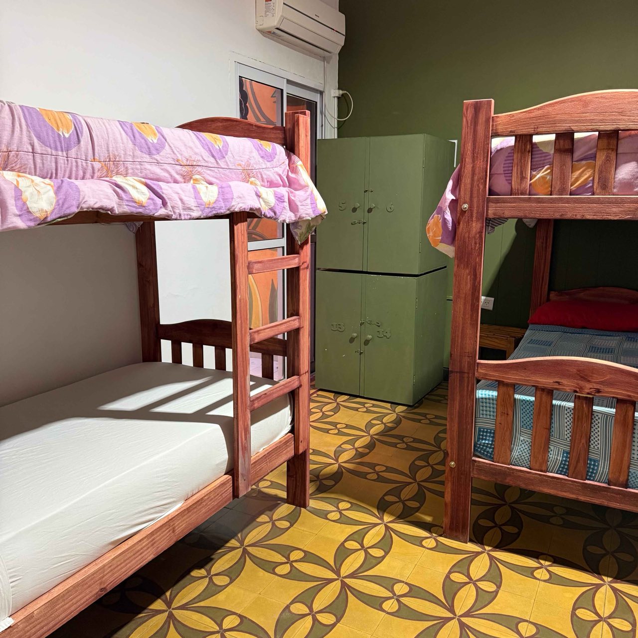 Dormitorio con cuchetas, lockers verdes numerados y aire acondicionado