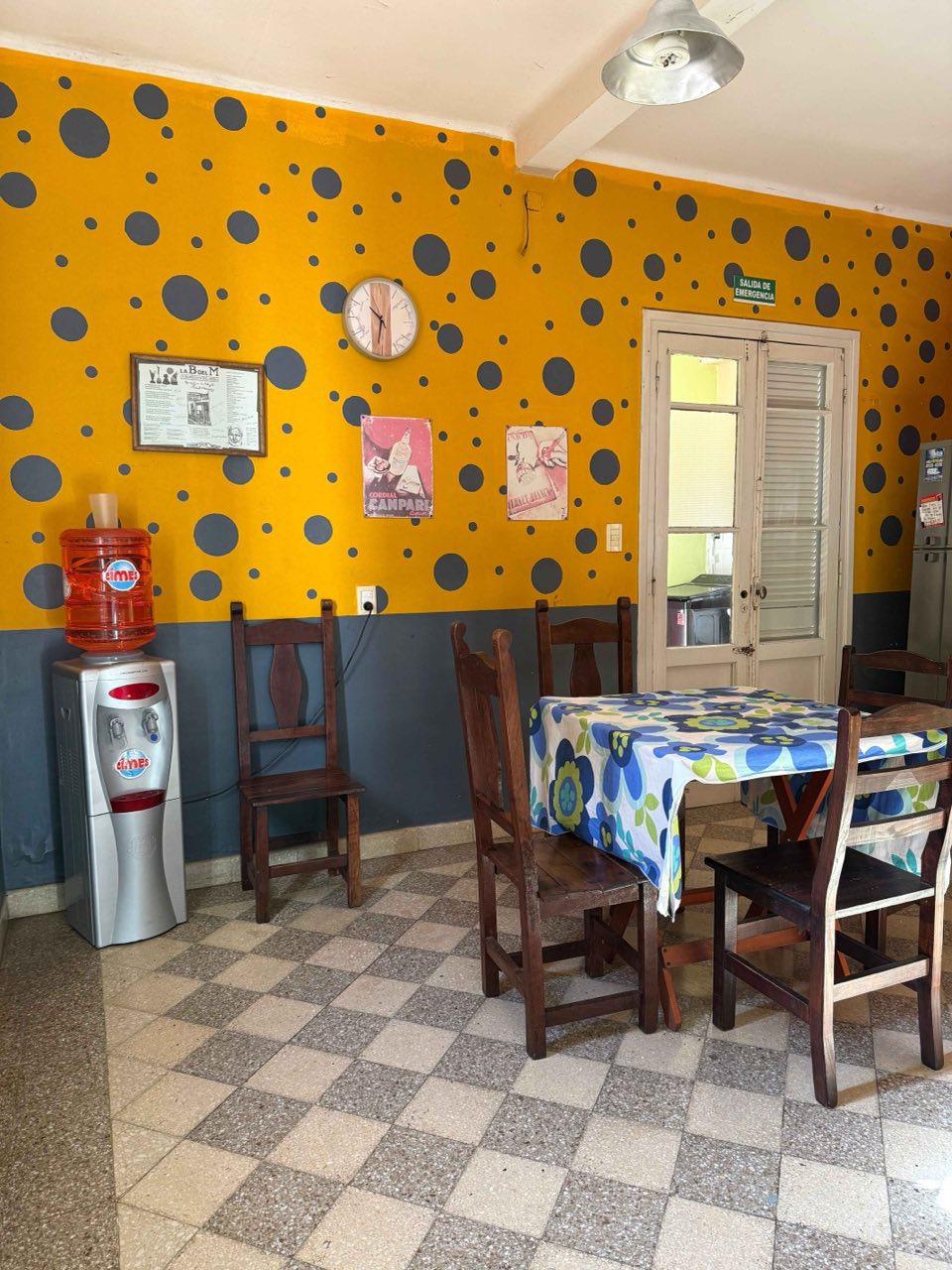 Comedor con paredes amarillas, dispenser de agua y mesa con sillas