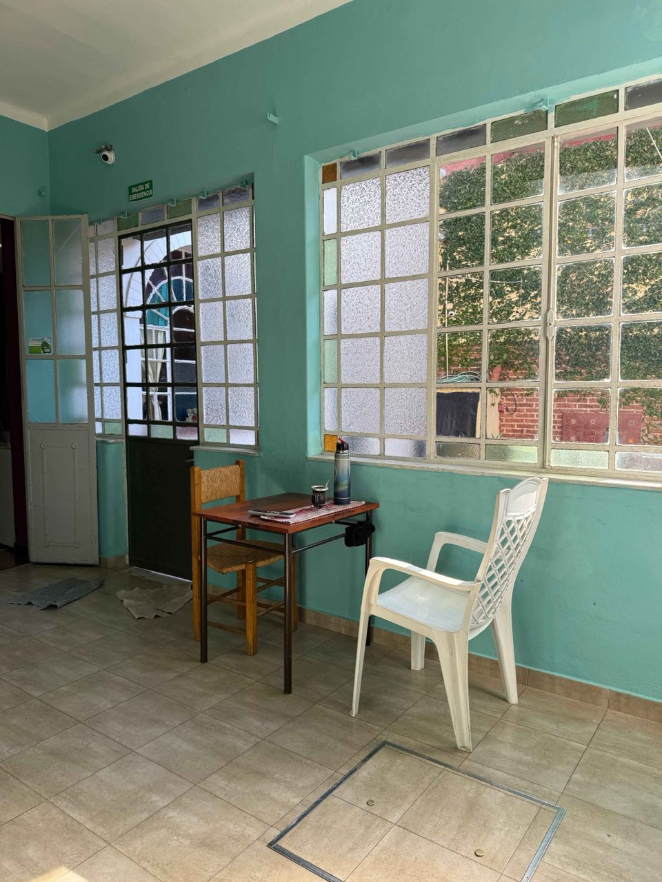 Galería interior con grandes ventanales, mesa y mate