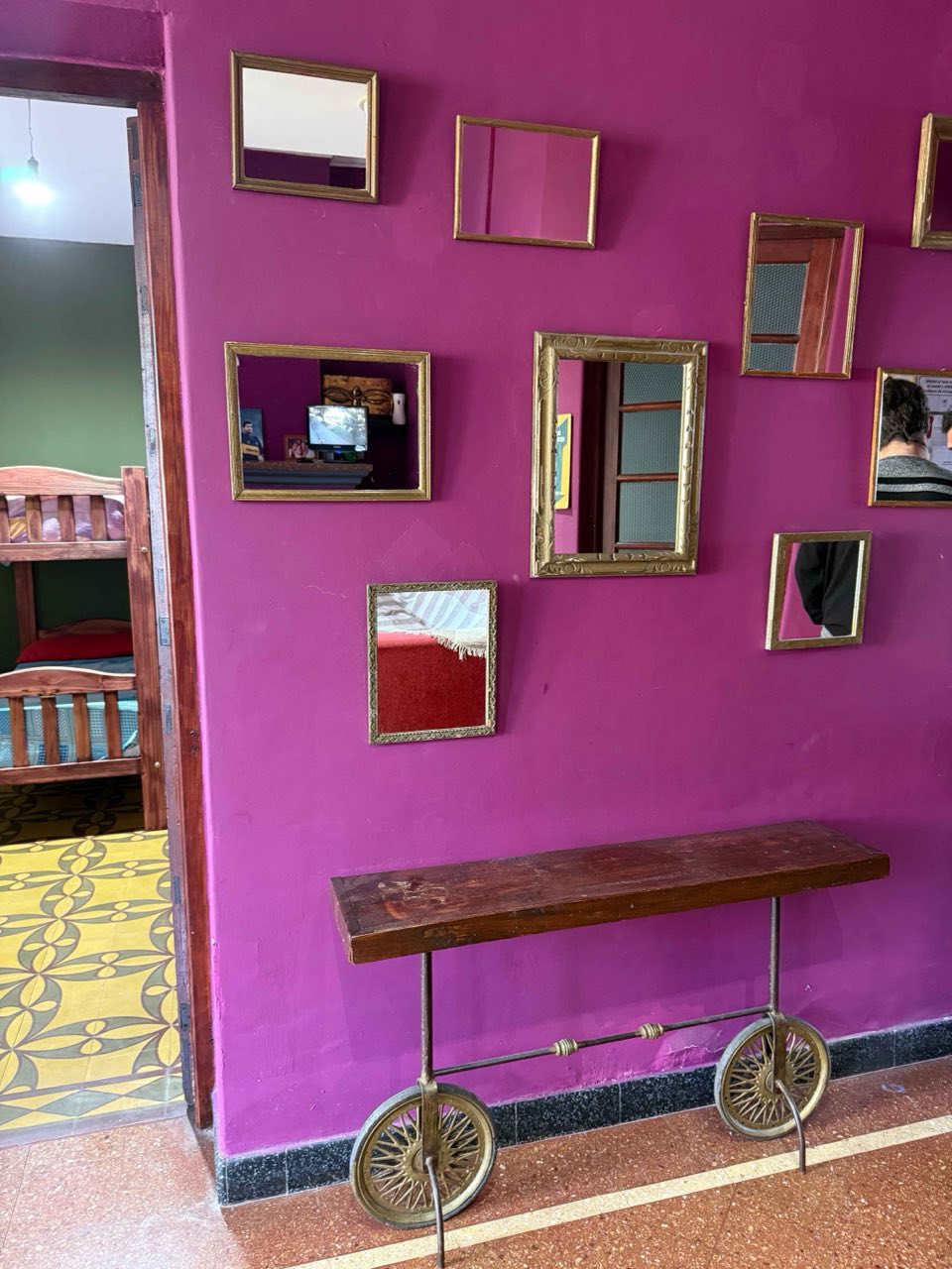 Pared fucsia decorada con espejos antiguos y acceso a un dormitorio