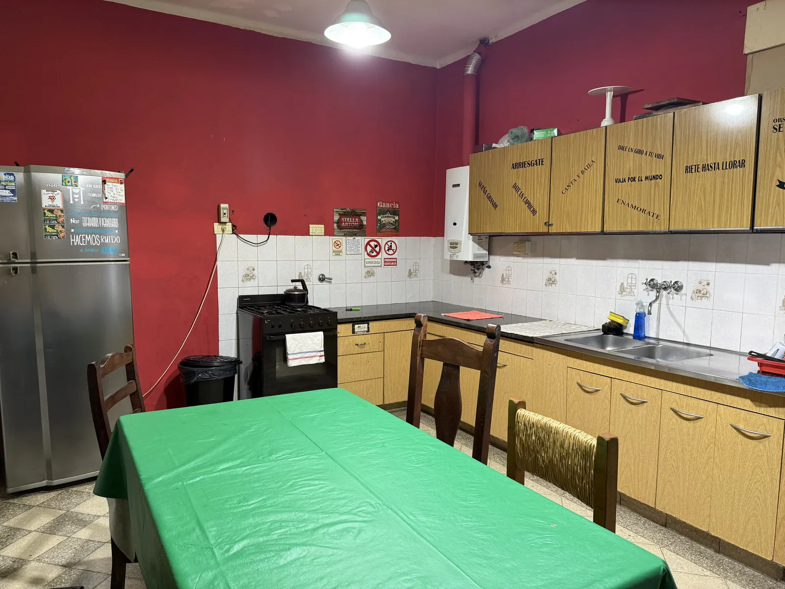 Cocina comedor con heladera, alacenas y mesa larga con mantel verde
