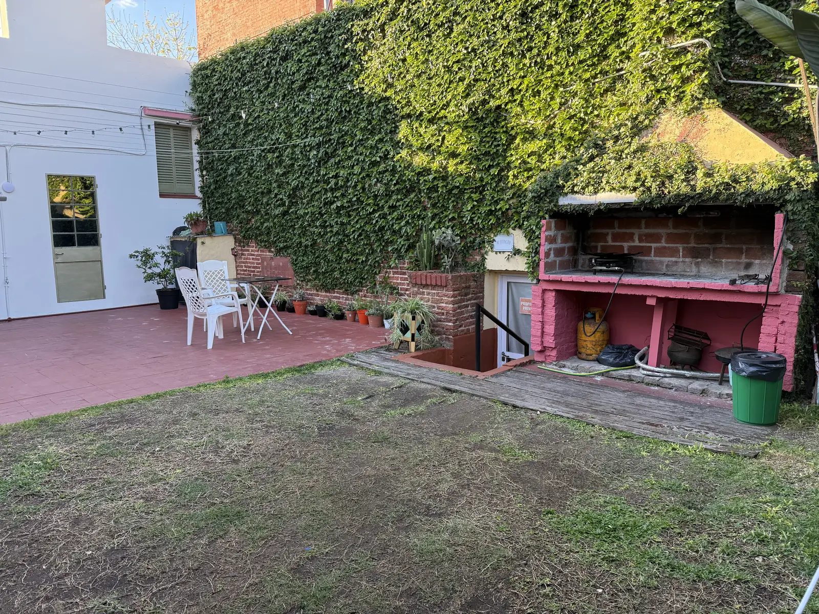 Asador de ladrillo junto al jardín con pared cubierta de enredadera