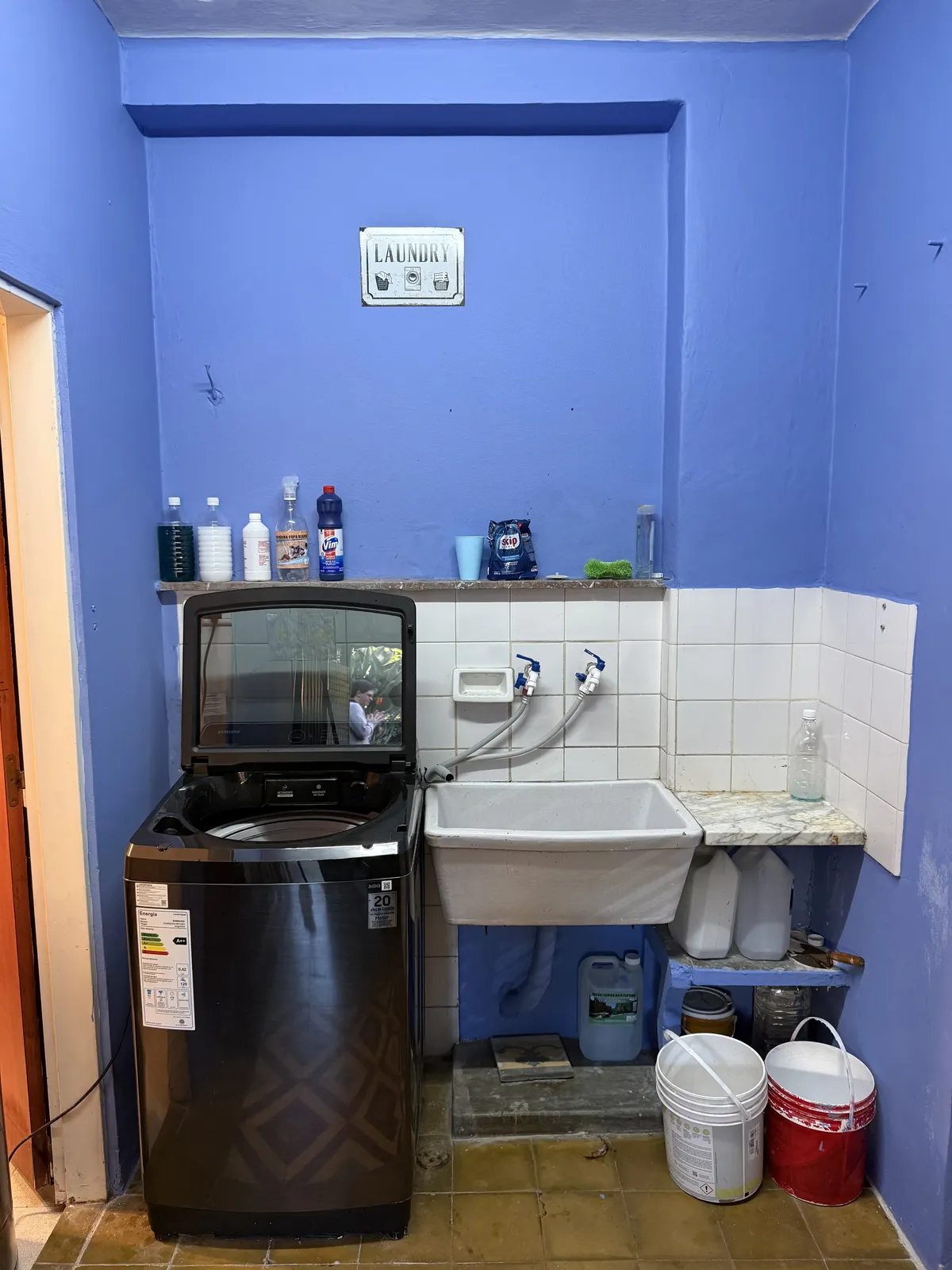 Lavadero con lavarropas, pileta y cartel de laundry
