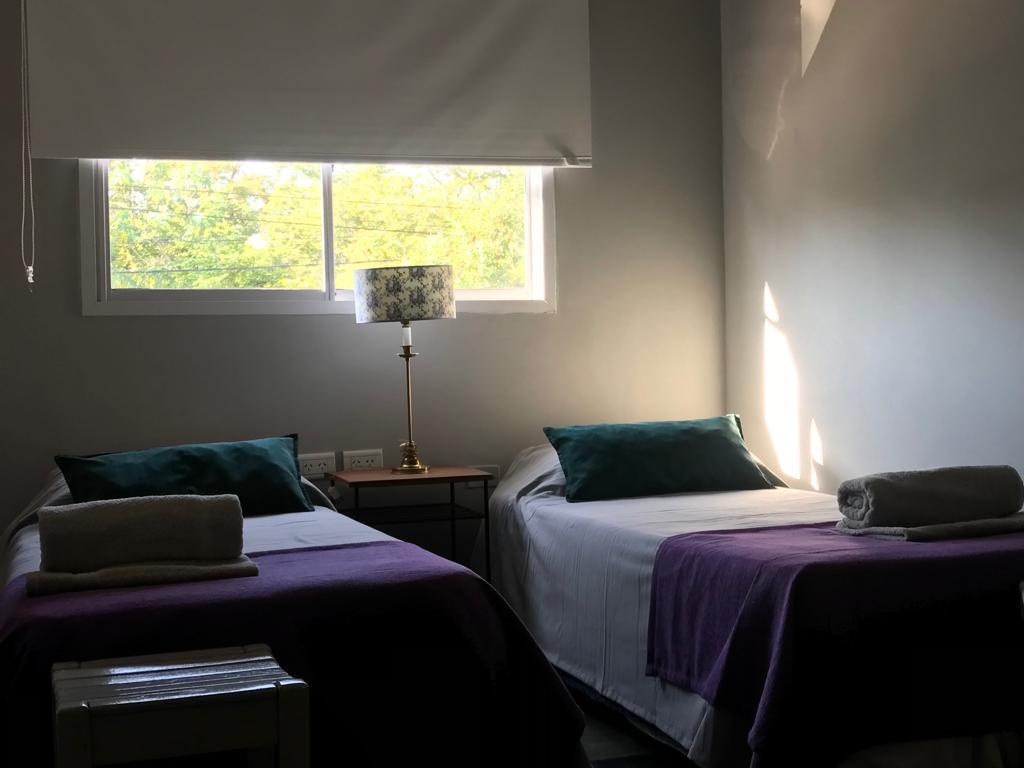 Dormitorio del dúplex con dos camas individuales y ventana con vista a los árboles