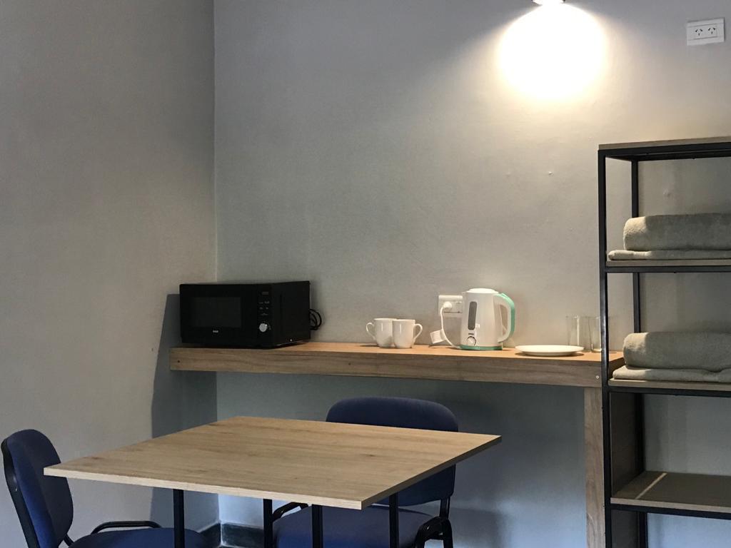 Rincón con desayunador del dúplex: mesa, sillas, microondas, pava eléctrica y toallas en el estante